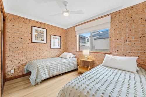 two beds in a room with a brick wall at Grand Pacific 1 Unit 1 - Ground Floor in Narooma
