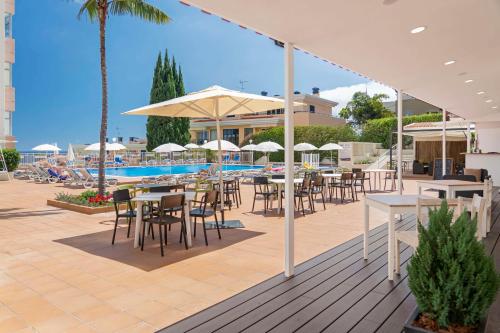 um pátio com mesas e cadeiras e uma piscina em Estrelicia Hotel no Funchal