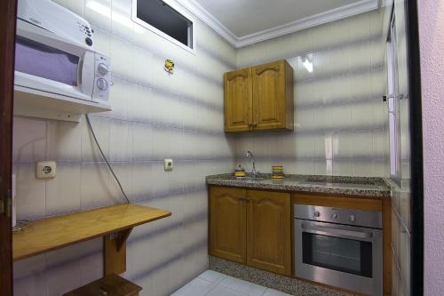 eine Küche mit einem Herd und einer Mikrowelle in der Unterkunft Apartamento Antonio Machado in Barbate
