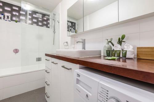 a white bathroom with a sink and a tub at Tranquil Botanical - A Slice of Riverside Paradise in Melbourne