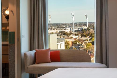 a couch in a hotel room with a large window at Holiday Inn & Suites Geelong by IHG in Geelong