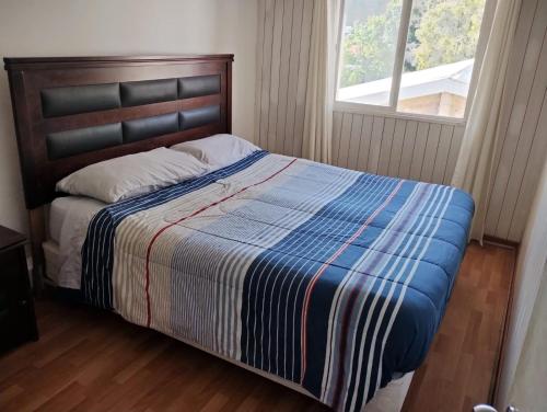 een slaapkamer met een bed met een gestreepte deken en een raam bij Wild Bellavista Hostel in Santiago