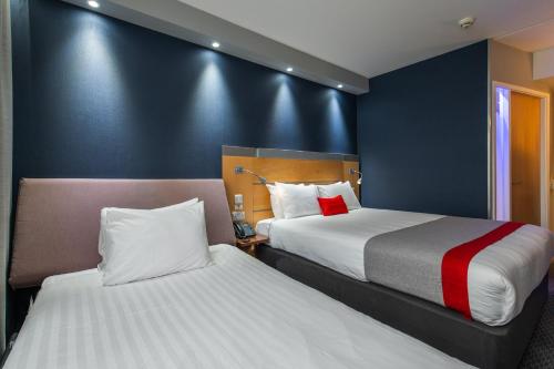 two beds in a hotel room with blue walls at Holiday Inn Express Ramsgate – Minster by IHG in Ramsgate