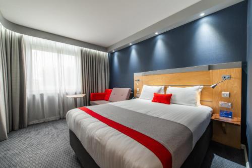 a hotel room with a large bed with red pillows at Holiday Inn Express Ramsgate – Minster by IHG in Minster
