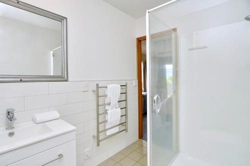 a bathroom with a glass shower and a sink at Watson Street - Bookahome in Akaroa