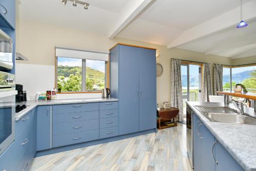 a kitchen with blue cabinets and a window at Watson Street - Bookahome in Akaroa