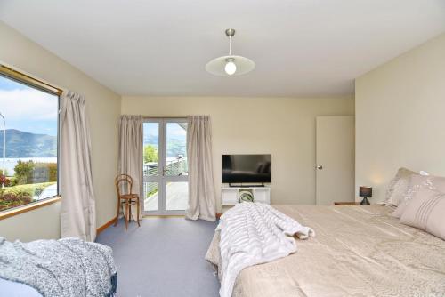 a bedroom with a large bed and a large window at Watson Street - Bookahome in Akaroa