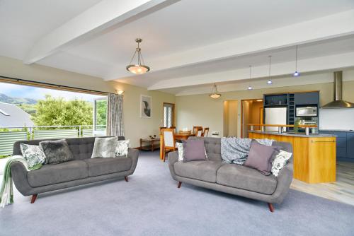 a living room with two couches and a kitchen at Watson Street - Bookahome in Akaroa