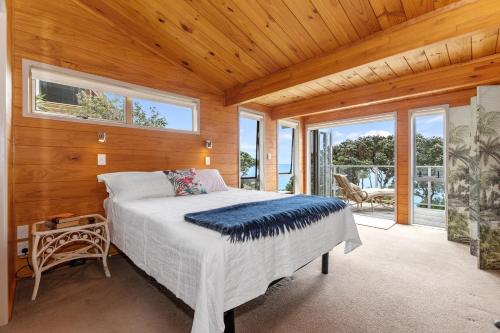 - une chambre avec un lit dans une pièce dotée de fenêtres dans l'établissement Coastal Calm - Langs Beach Holiday Home, à Waipu