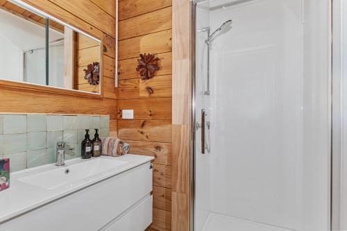 La salle de bains est pourvue d'un lavabo blanc et d'une douche. dans l'établissement Coastal Calm - Langs Beach Holiday Home, à Waipu