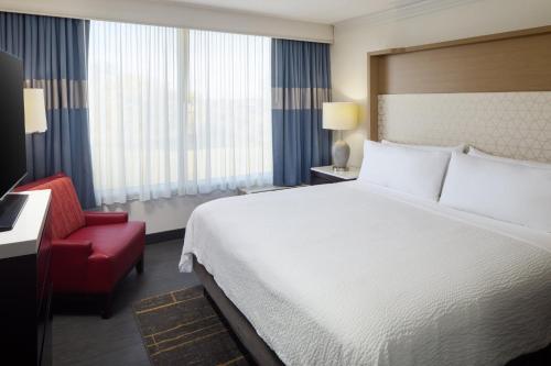 a hotel room with a bed and a red chair at Holiday Inn Weirton-Steubenville Area in Weirton