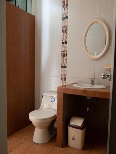 a bathroom with a toilet and a sink and a mirror at Hotel Queen in Lima