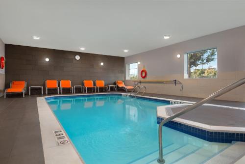 Holiday Inn Express Hotel & Suites Barrie, an IHG Hotel في باري: حمام سباحة في غرفة الفندق مع كراسي برتقالية