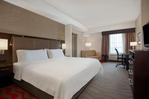 a hotel room with a large bed and a desk at Holiday Inn Express Hotel & Suites Barrie by IHG in Barrie