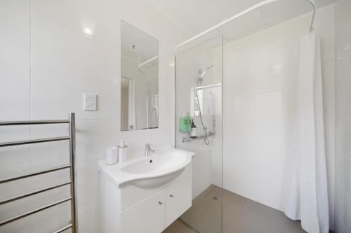 a white bathroom with a sink and a shower at Apartment 3 in Auckland