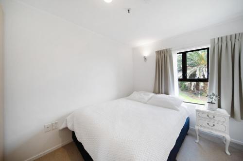 a white bedroom with a bed and a window at Apartment 3 in Auckland