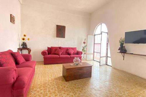 a living room with two red couches and a coffee table at Casa Polita in Chiapa de Corzo
