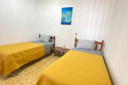 two beds in a room with yellow sheets at Casa Polita in Chiapa de Corzo