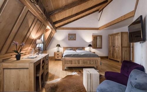 a bedroom with a bed and a desk and a couch at Romantik Hôtel l'Etoile in Charmey