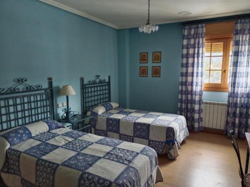 two beds in a room with blue walls at Hotel Pico Espiguete in Alba de los Cardaños
