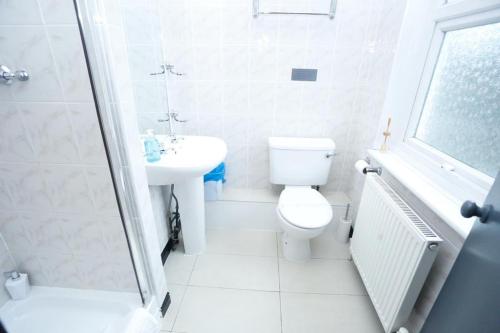 a white bathroom with a toilet and a sink at Acorn Lodge Hotel Gatwick & Parking in Horley