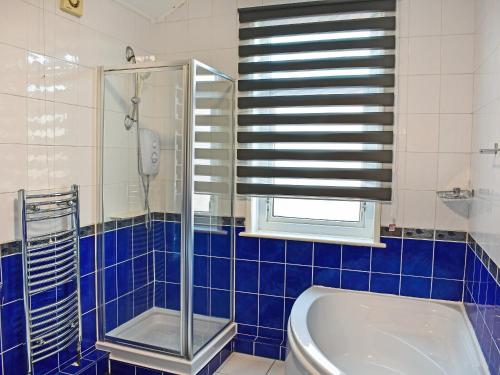 a blue tiled bathroom with a shower and a tub at Seymour House in Bishop Auckland