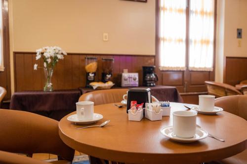 une table avec des tasses et des soucoupes en haut dans l'établissement Hotel Estefania, à Morelia