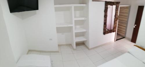 a white room with a tv and a white tile floor at Hotel Ambeyma in Garzón