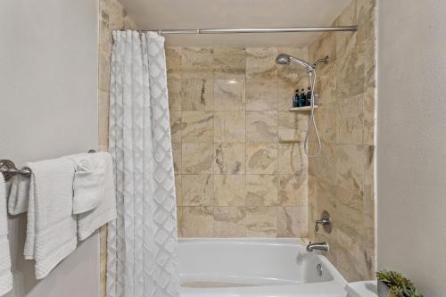 y baño con bañera y cortina de ducha. en Island Surf 304 - Renovated, Ocean Views, Split AC, en Kihei