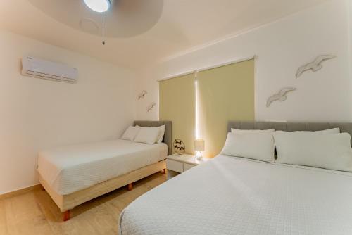 a white bedroom with two beds and a window at Amazing Caribbean Ocean view at Villas Marlin in Cancun in Cancún