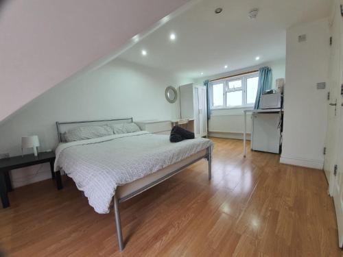 a white bedroom with a bed and a table at Eastwood Rooms in Goodmayes
