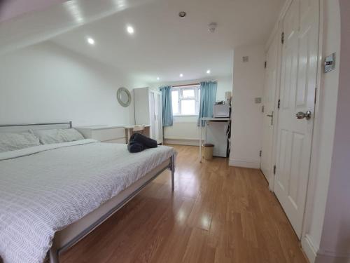 a white bedroom with a bed and a window at Eastwood Rooms in Goodmayes