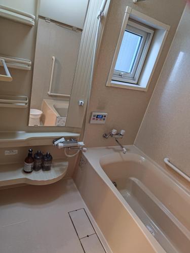 W łazience znajduje się wanna, umywalka i lustro. w obiekcie Anna's House w mieście Sapporo