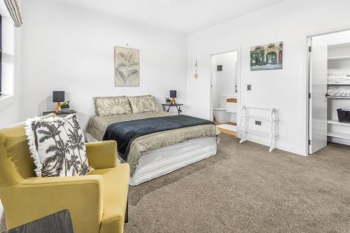 1 dormitorio con 1 cama y 1 silla amarilla en Upper Bow Retreat - Raglan Holiday Apartment en Raglan