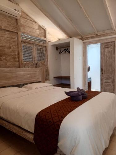 a bedroom with a large bed with a wooden wall at The Blue Joglo Jogja in Yogyakarta