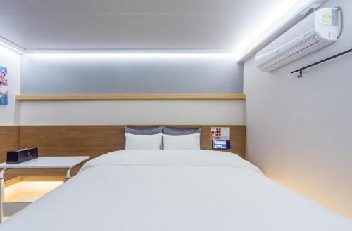 a bedroom with a large white bed and a desk at Hotel The Araboda in Gwangju
