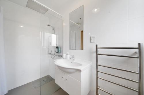 a white bathroom with a sink and a mirror at Apartment 4 in Auckland