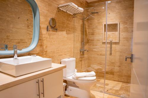a bathroom with a toilet and a sink and a shower at Fortunity Beach Tower-2 BDR with pool view in San Felipe de Puerto Plata
