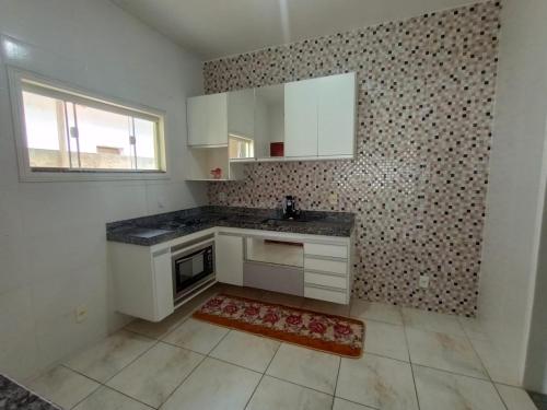 eine leere Küche mit weißen Schränken und einem Fenster in der Unterkunft Casa em iguaba grande in Iguaba Grande