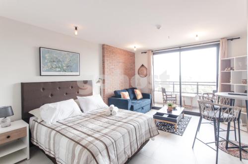 a bedroom with a bed and a couch and a chair at Comfortable Los Laureles Loft in Asuncion