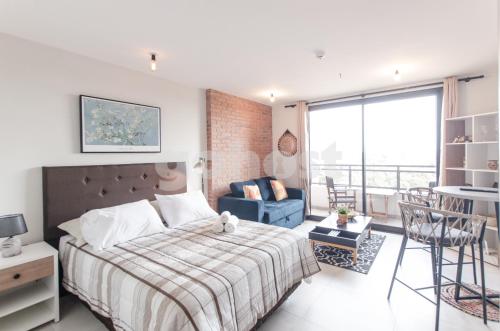 ein Schlafzimmer mit einem Bett, einem Sofa und einem Stuhl in der Unterkunft Comfortable Los Laureles Loft in Asunción