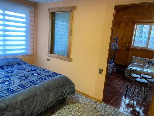 a bedroom with a bed and a table and a window at Alojamiento Pichidangui in Pichidangui