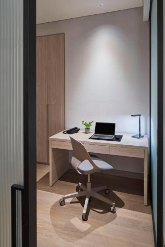 an office with a desk with a laptop and a chair at PARKROYAL Serviced Suites Jakarta in Jakarta