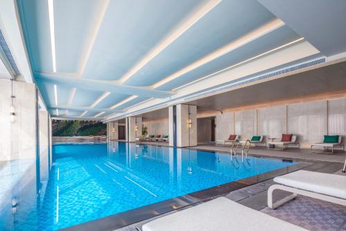 a large swimming pool with blue water in a building at Sheraton Pujiang in Jinhua
