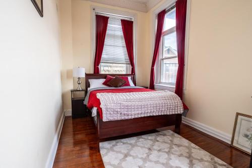 a bedroom with a bed and two windows with red curtains at Cozy historic 3rdfl apartment in Baltimore