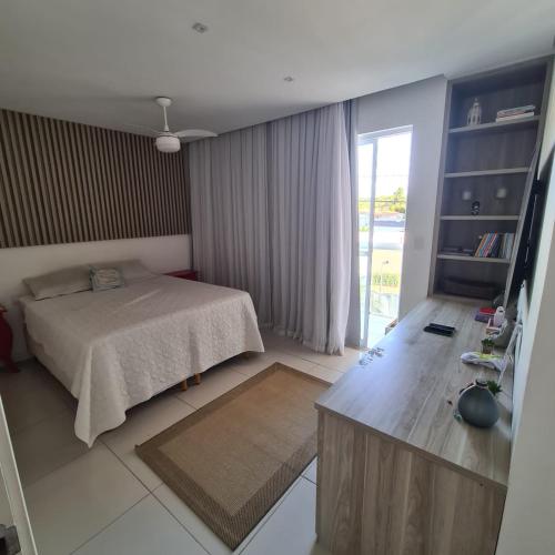 a bedroom with a bed and a sliding glass door at Casa com piscina a 800 metros da praia de Buraquinho in Lauro de Freitas
