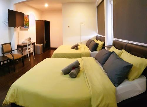 Habitación de hotel con 2 camas con sábanas amarillas en CassaKaseh Guest House, en Pantai Cenang
