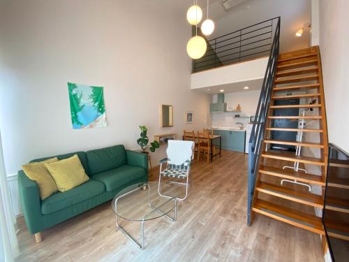 a living room with a green couch and a staircase at La Pause Pension in Seogwipo