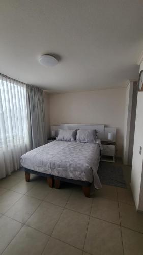 a bedroom with a large bed with pillows on it at Edificio Matiz Central Iquique in Iquique