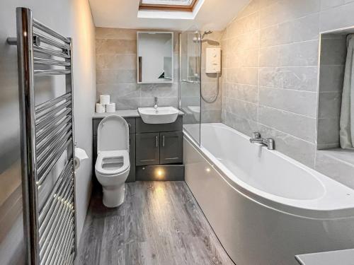 a bathroom with a tub and a toilet and a sink at Lingmoor View in Ambleside